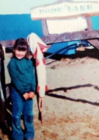 Suzanne as a young girl at Dore Lake, standing beside a big catch